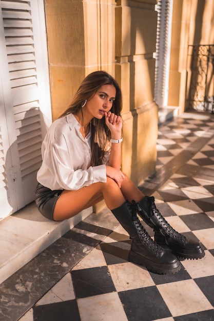 Lifestyle a young brunette in a black leather skirt and a white shirt