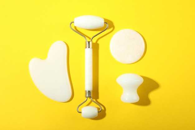 Lifting and toning treatment concept with gua sha on yellow background