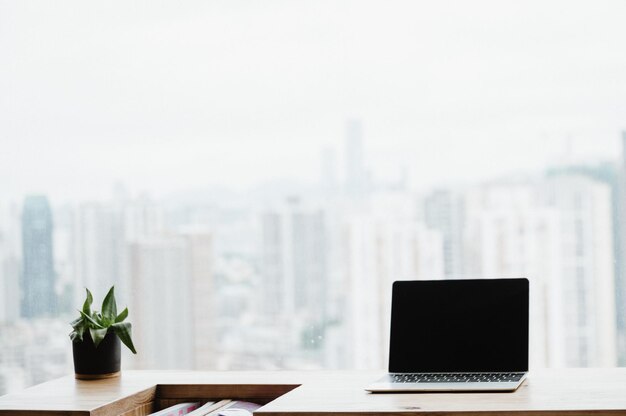 Light apartment interior with minimalist workplace and transparent chair and table with laptop and books on a white marble concrete floor near window with a city view