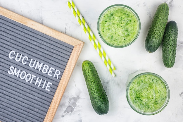 On a light background, two glasses of green freshly squeezed juice.