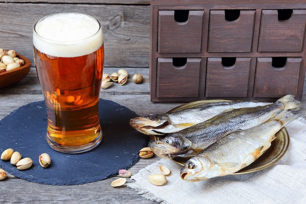 Light beer and stockfish - smelt and vobla, traditional russian beer snack, on a wooden gray table