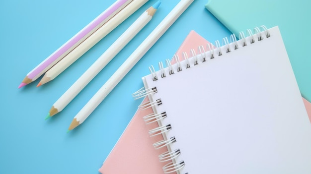 Light blue background showcases two white notebooks with light blue pink and white colored pencils