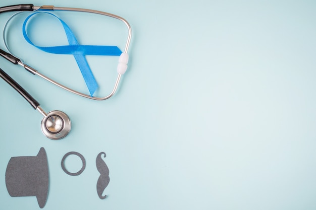 Light blue ribbons with black mustache, top hat and stethoscope on blue , prostate cancer awareness,  Men health awareness, November blue. copyspace.