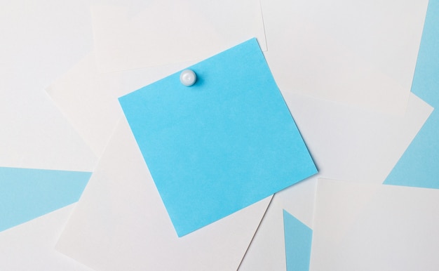 On a light blue surface, white square pieces of paper