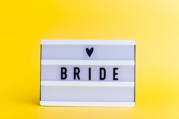 light box with text, BRIDE, on yellow wall