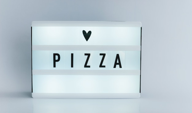 light box with text, PIZZA on white wall