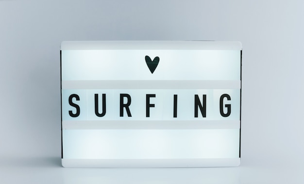 light box with text, SURFING on white wall