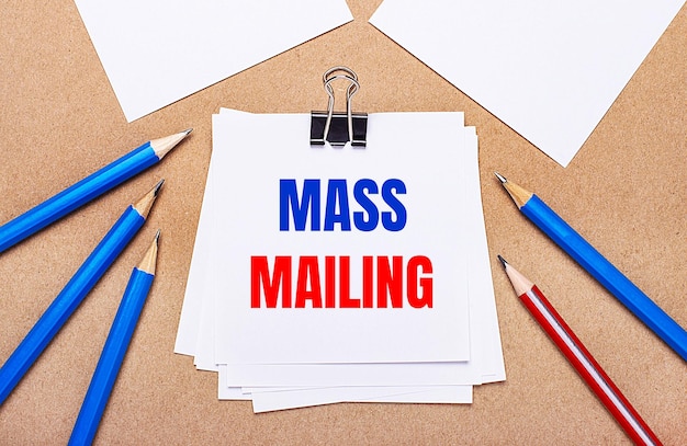 On a light brown background blue and red pencils and white paper with the text MASS MAILING