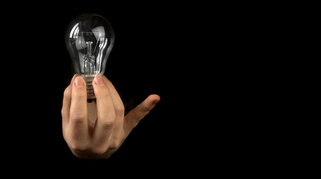 Light bulb hold fingers on black background with copy space photo, concept of new business idea photo