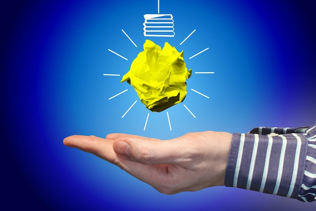 Light bulb icon made with crumpled paper and human hand idea creativity concept