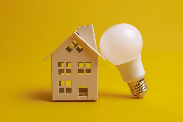 Light bulb and miniature house model isolated on yellow The concept of save energy with LED lights