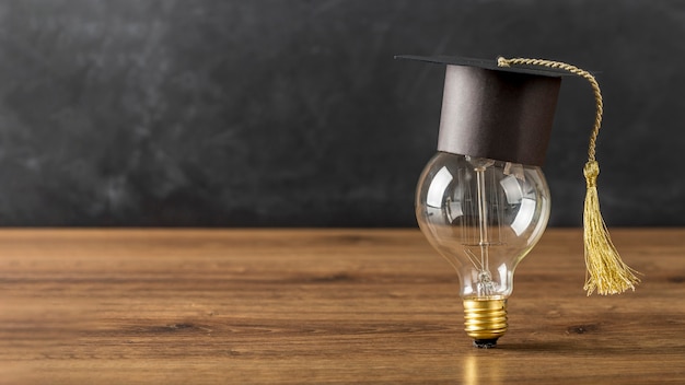 Light bulb with graduation cap and copy space