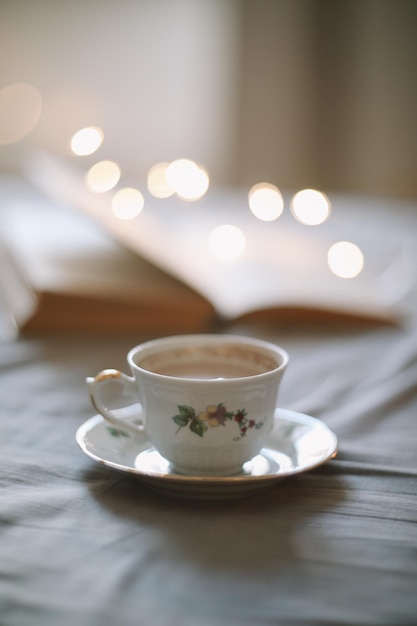 Light cozy bedroom Coffee or tea cup and an open book on the bed Spring still life Breakfast in bed