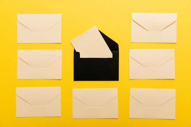 Light envelopes with card inside isolated on yellow background Top view