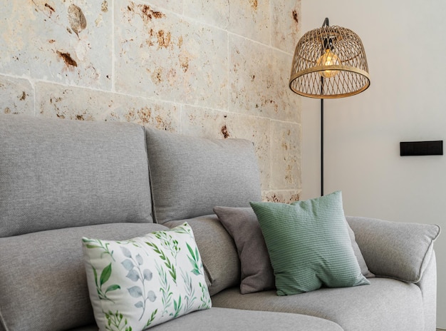 Light grey living room sofa with pillows in front of a natural stone wall