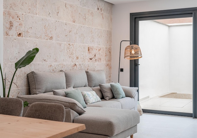 Light grey living room sofa with pillows in front of a natural stone wall