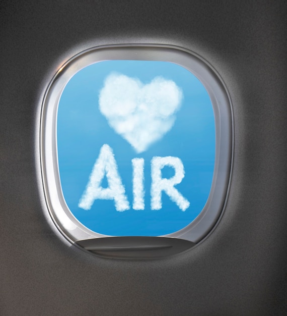 Light heart symbol made from clouds and word Air on a blue sky background through an aircraft window with copy space. Travel and transportation concept.