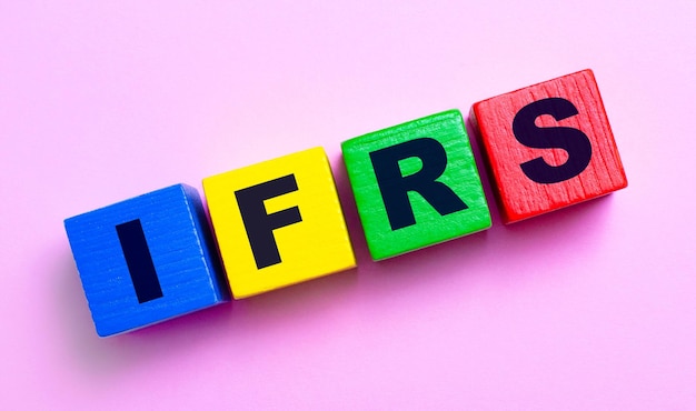 On a light pink background multicolored wooden cubes with the text IFRS International Financial Reporting Standards