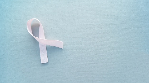 Light pink ribbon on the grey background.Breast cancer awareness and Abdominal cancer awareness. World cancer day. Space for text