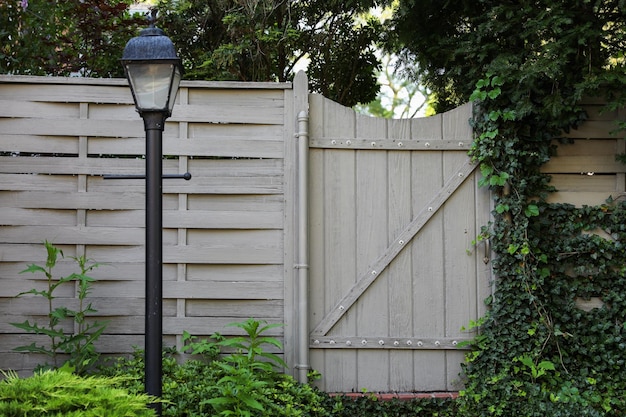 A light pole is in front of a wooden fence.