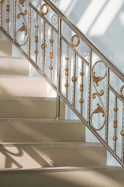 Light and shadow on surface of stainless steel handrail with beige tile staircase of vintage home 