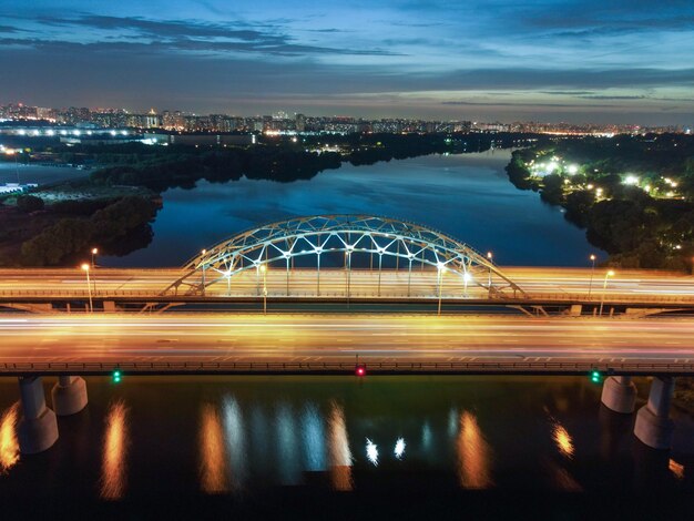 Light trails on bridge in city against sky at night