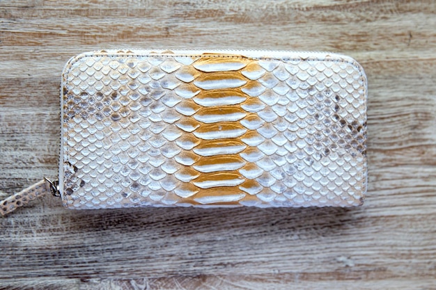 Light wallet from trendy snake python skin on wooden white background