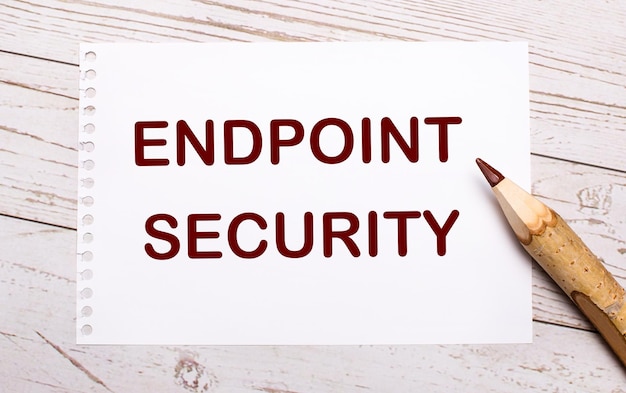 On a light wooden background a colored pencil and a white sheet of paper with the text ENDPOINT SECURITY