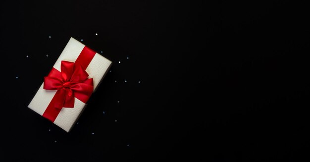 Photo light yellow gift box with red bow on black background