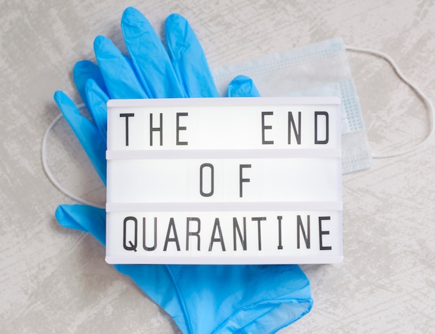 Lightbox and text end of quarantine, medical gloves and protective mask