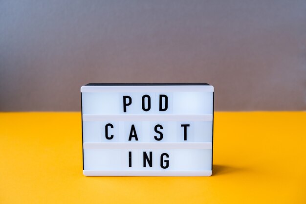 Lightbox with text podcasting in minimalistic isometric style. Trendy colors. Grey and yellow. New technologies. Millenial. Blogger, podcaster. Podcasting lettering. Audiobooks.