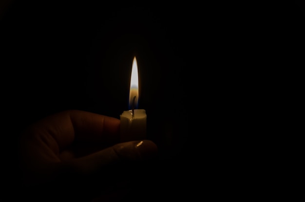 lighted candle in the dark