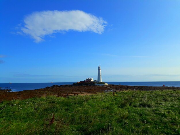 Lighthouse by sea against blue sky