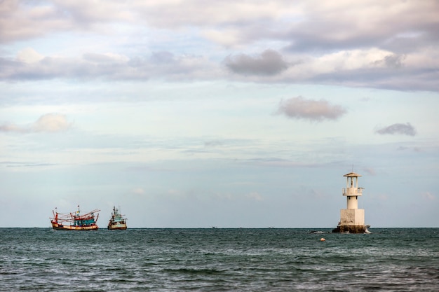 Lighthouse and fishing boat in the sea.