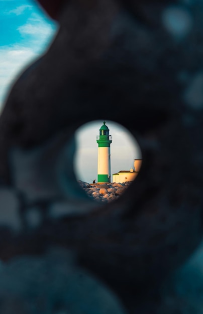 Photo a lighthouse is seen through a hole in the rock