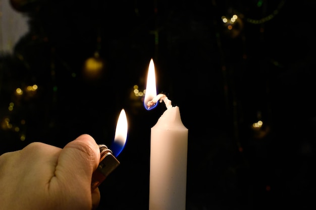 Lighting a candle with a lighter. burning candle in the dark