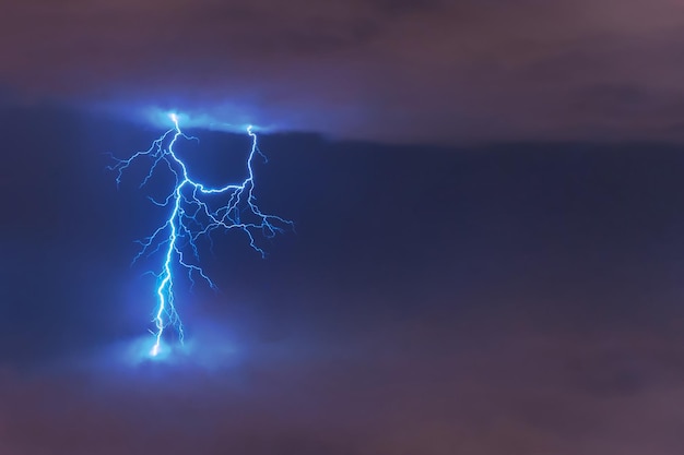 Lightning strike flash electric discharge between clouds at night