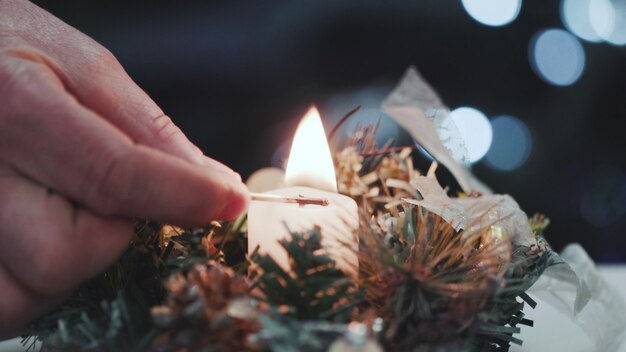 Lights the candles at the Christmas table. Close-up of a man's hand lighting a candle