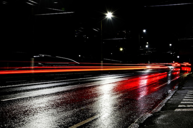 Lights of cars at night. Street lights. Night city. Long-exposure photograph night road. Colored bands of light on the road. Wet road after rain.