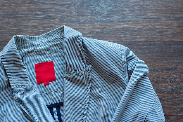 Photo lightweight striped cotton jacket with a fashionable brooch on wooden background