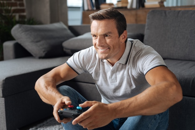 Like a kid. Handsome charismatic attentive guy sitting in his living room