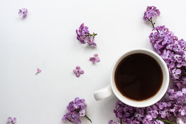 Lilac and cup of coffee in flat style on white wooden background Beautiful spring Overhead view Flat lay top Summer season Natural spring style