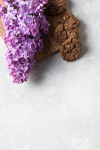 Lilac flowers with chocolate cookie on light grey background