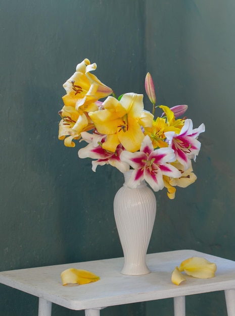 Lillies in white vase on blue background