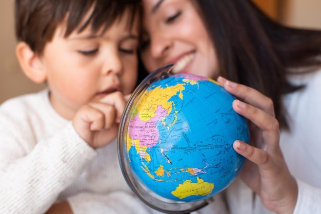 Liltle Preschooler Kid learing geography with a globe map and teacher educador help. Homeshooling. Learning Community. Montessori School