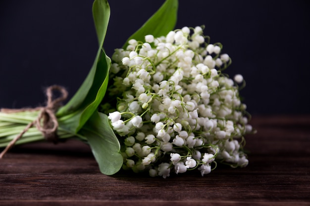 Lily of the valley on dark wooden table. Lily of the valley bouquet.