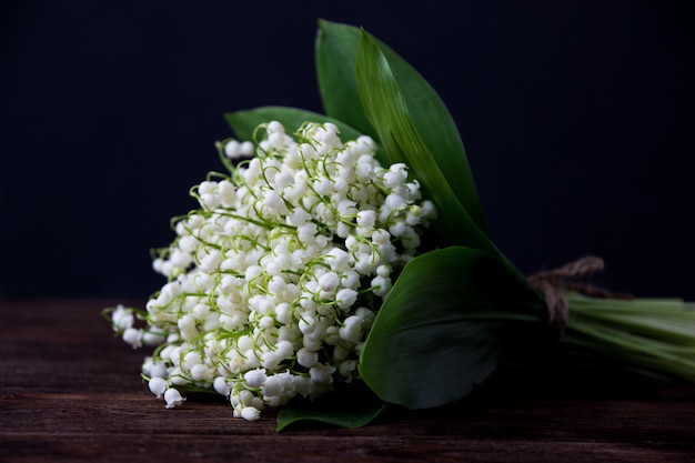 Lily of the valley on dark wooden table. Lily of the valley bouquet.