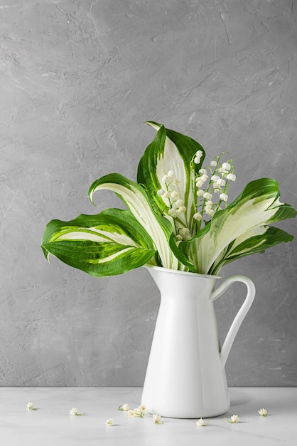 Lily of the valley flowers bouquet in vase on gray background vertical orientation womans day or wedding background with copy space