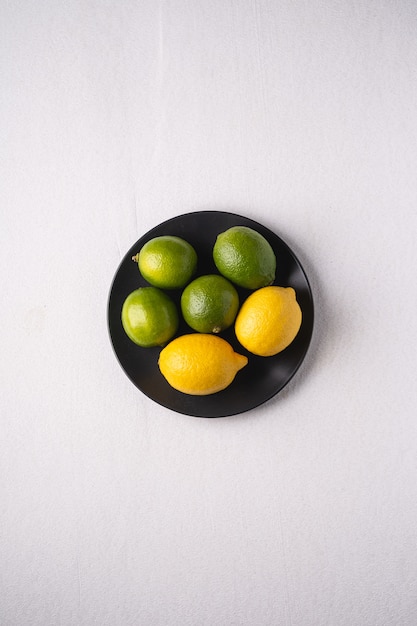 Lime and lemon sour fruits in black plate on white