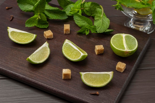 Lime wedges brown sugar and sprigs of mint on a board